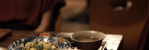 A blue and white patterned ceramic bowl holds stir-fried vegetables beside a simple gray soup cup.