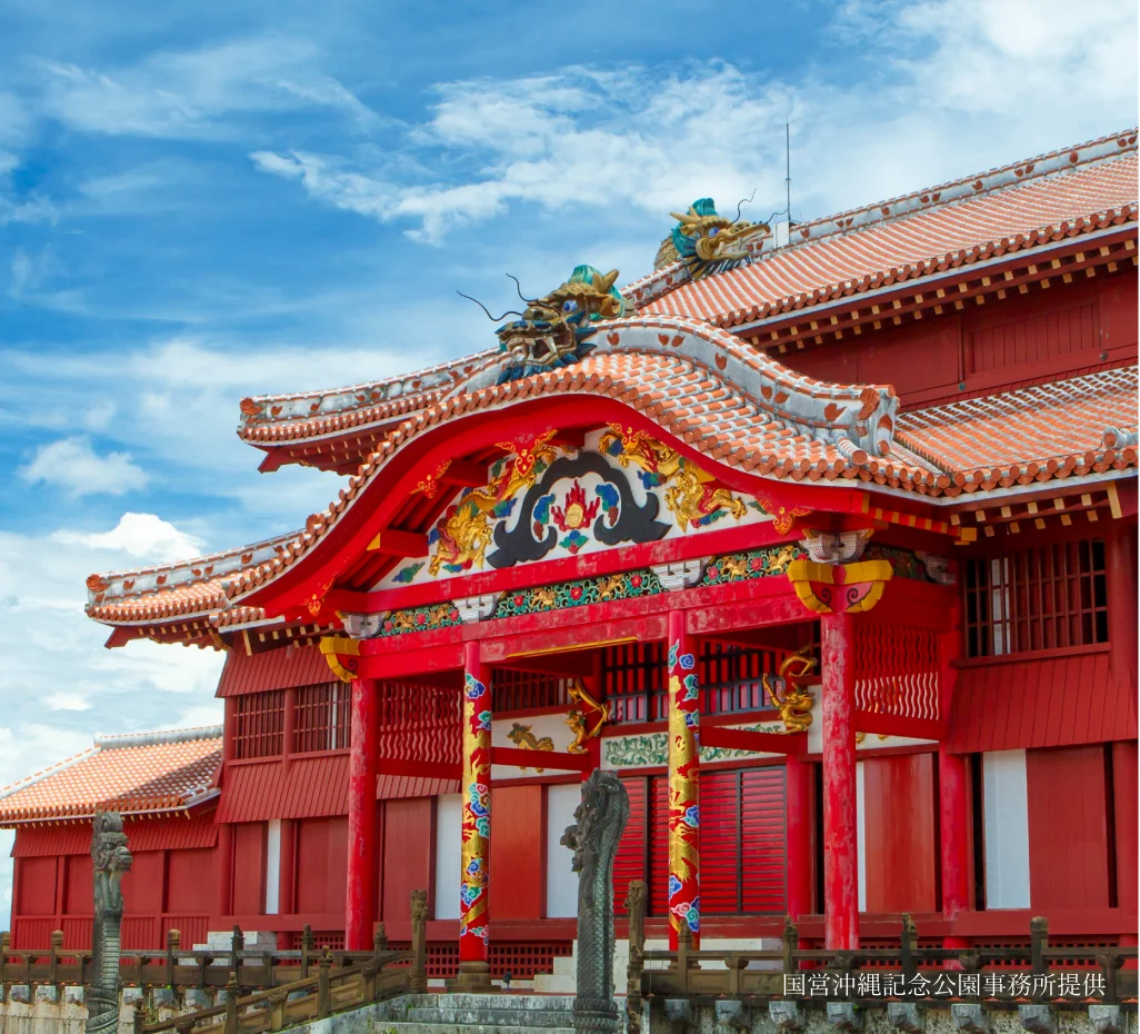 The ornate crimson Shureimon Gate features curved tiled eaves and intricate wooden brackets at Shurijo Castle.