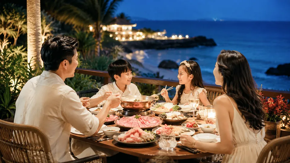 Keluarga menikmati jamuan shabu-shabu di meja kayu terbuka dengan latar belakang pemandangan laut malam di Okinawa.